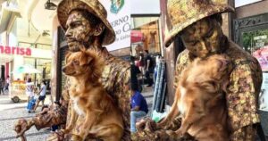 Cagnolino aiuta il suo padrone e finge anche lui di essere una statua: i due artisti di strada sono una coppia inseparabile